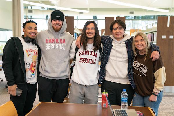 Five students smile and pose together